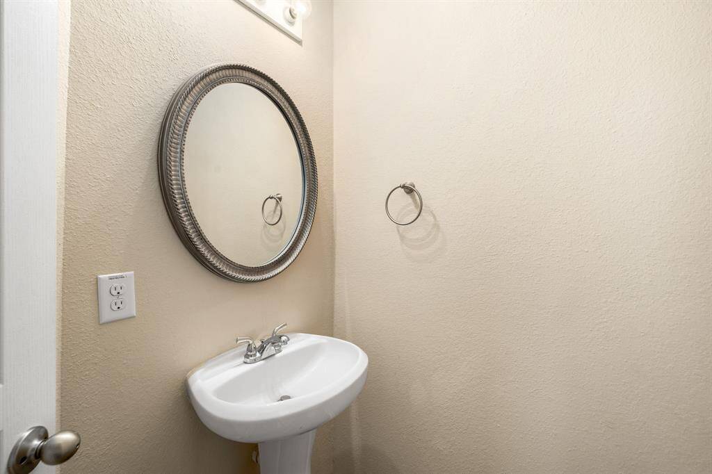 Convenient main-level half bath featuring a stylish pedestal sink and decorative mirror.