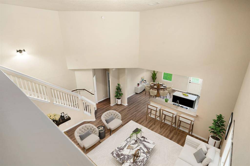 An impressive view from the upstairs landing reveals soaring ceilings, stylish bar seating, and an open-concept layout for seamless entertaining. *Virtually Staged