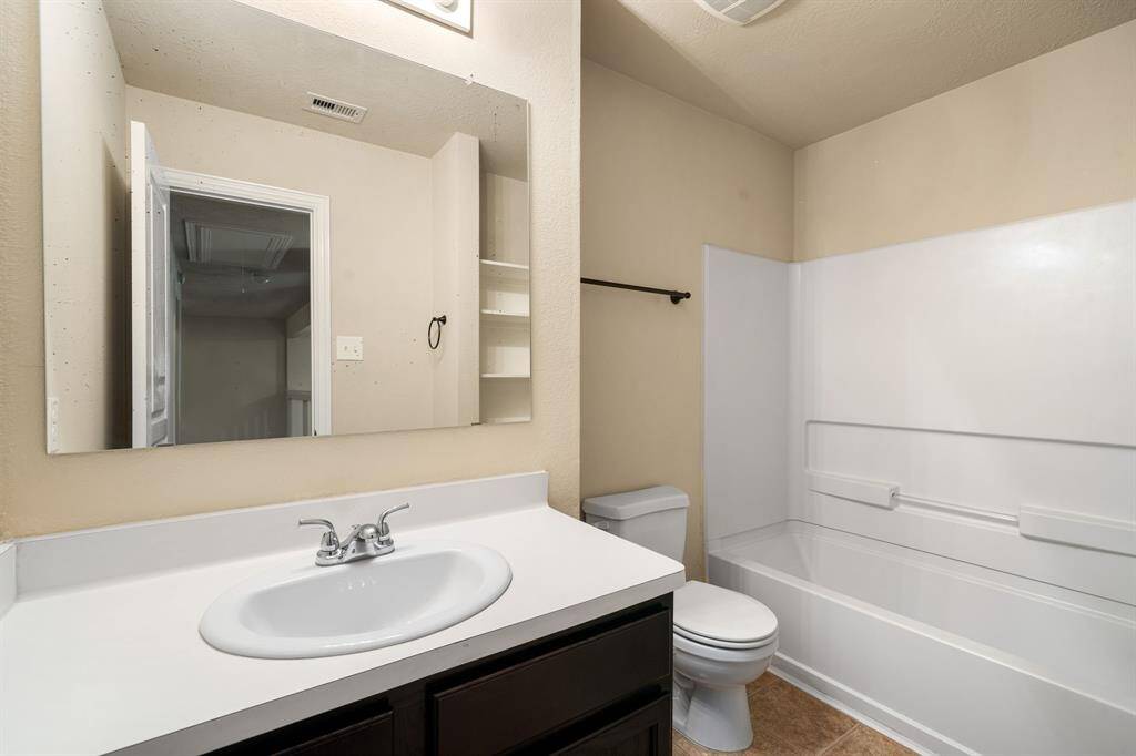 Secondary bathroom features light countertops and cabinets, custom paint, shower/tub combo with tile surround, large mirror, tile floors, sleek fixtures and modern finishes, plenty of space to accommodate any visiting family or guests.