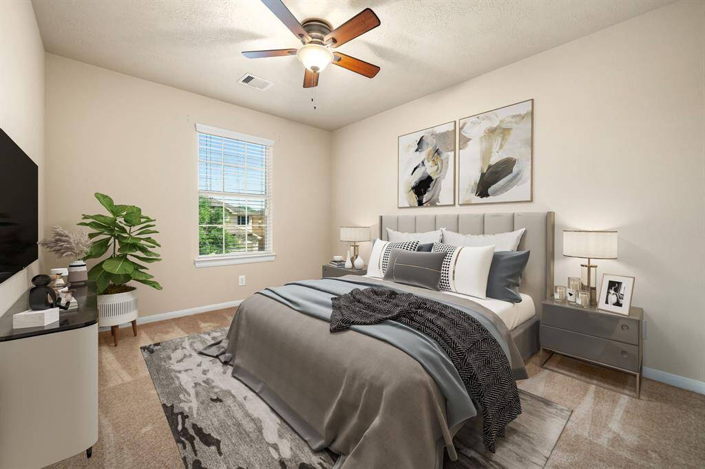Secondary bedroom features plush carpet, custom paint, dark stained ceiling fan with lighting and a large window with privacy blinds. *Virtually Staged