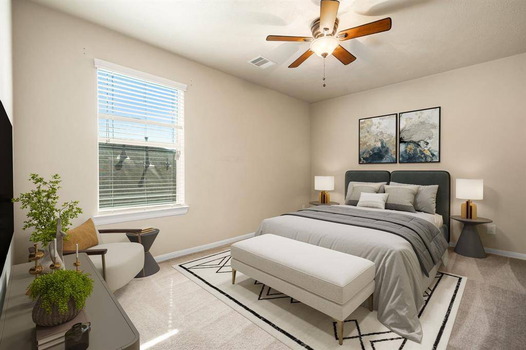 Secondary bedroom features plush carpet, a dark stained ceiling fan with light, neutral paint, and a large window providing plenty of natural light. Perfect
