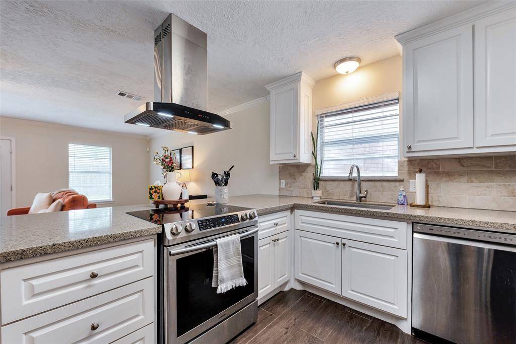 Quartz countertops and a freestanding stainless steel vent hood.