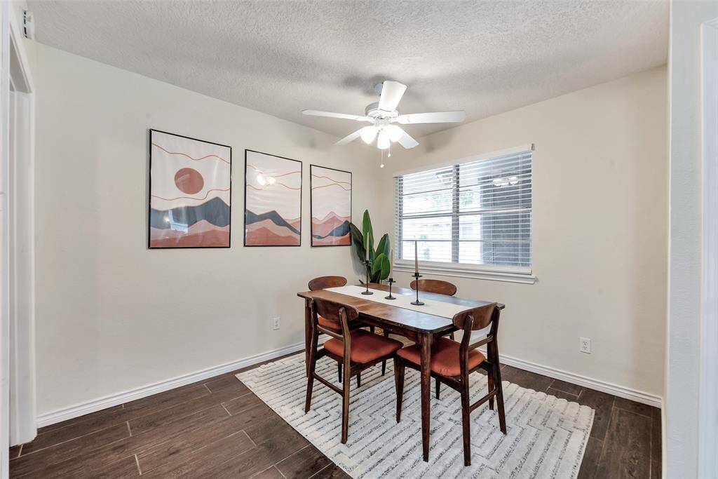 Dining room with wood look tile and a lighted ceiling fan.