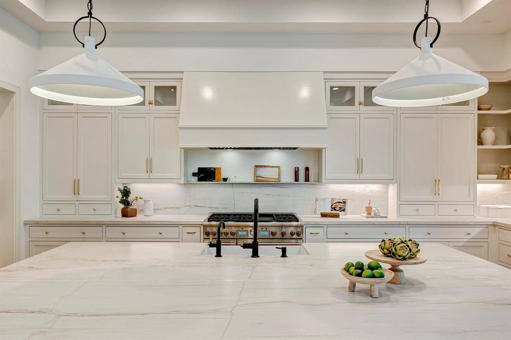 Stunning chef's kitchen featuring custom inset cabinetry, concealed undercabinet lighting, and honed Mont Blanc quartzite countertops with an integrated shelf ledge backsplash. A sleek apron-front sink and spacious island complete this magazine-worthy space that's perfect for entertaining.