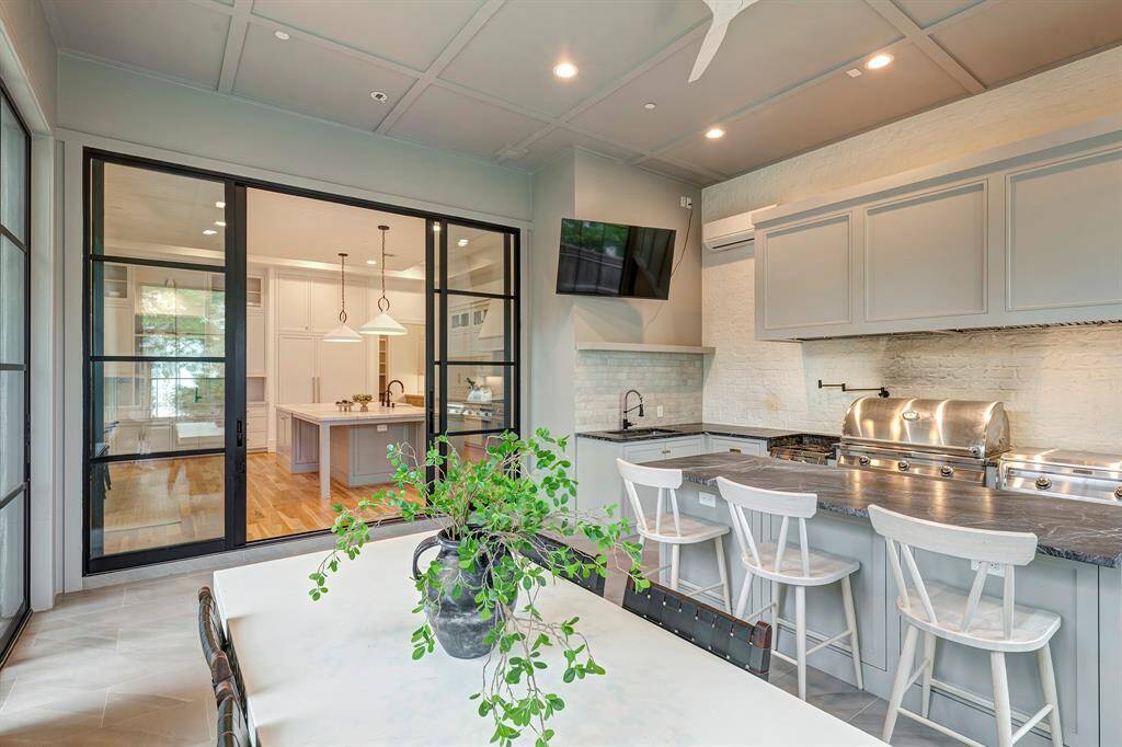 This fabulous indoor/outdoor living space and kitchen off the main kitchen is designed for both entertaining and everyday cooking. Enclosed, insulated, and equipped with its own A/C unit, it functions seamlessly as both an indoor and outdoor space. The custom-built floor-to-ceiling quad-folding metal-glass doors create perfect flow for indoor-outdoor entertaining.