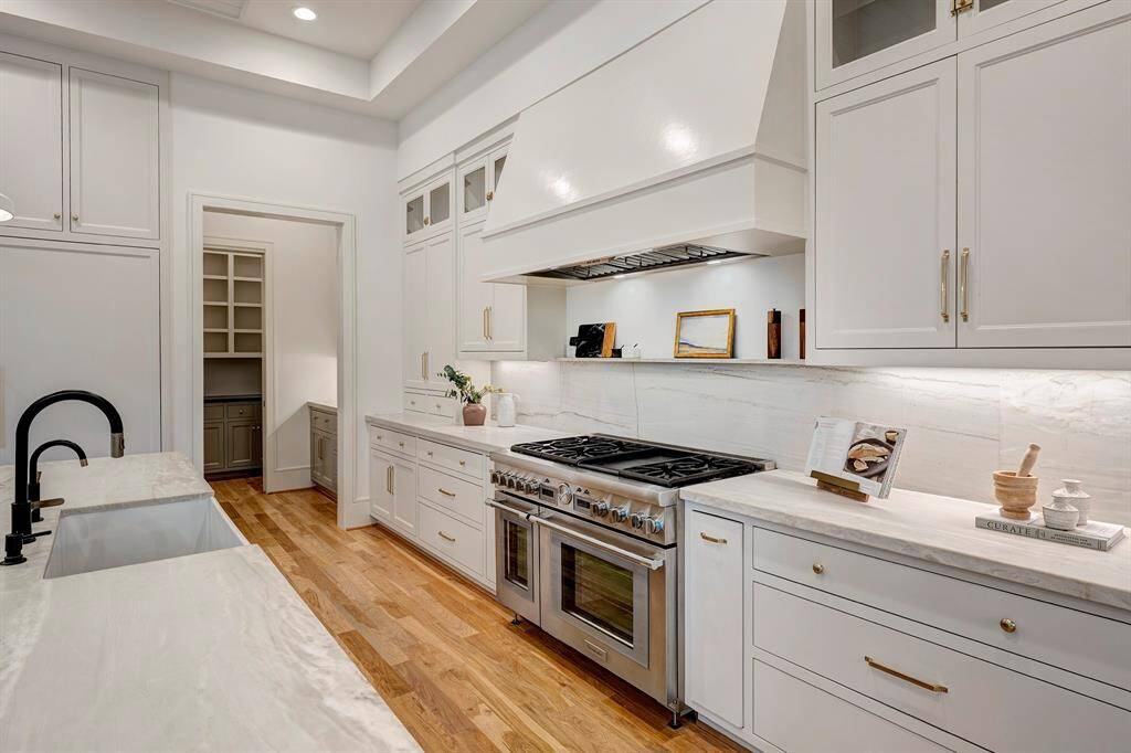 The chef’s kitchen is a true showstopper—outfitted with Thermador appliances, including a 48-inch gas range, double ovens, and paneled refrigerator and freezer. Honed quartzite countertops, custom inset cabinetry, and a stunning backsplash with a shelf ledge complete the space.