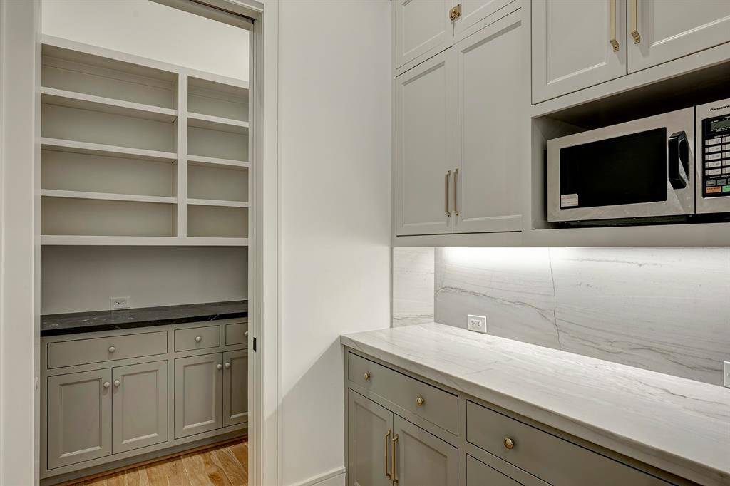 Dedicated service pantry and a spacious walk-in pantry—each concealed behind sleek pocket doors for a clean, streamlined look. These spaces offer an abundance of storage with custom built-in shelving, perfect for keeping everything from cookware to entertaining essentials neatly organized and easily accessible. Whether you're hosting or meal prepping, these thoughtfully designed pantries provide the perfect blend of form and utility.