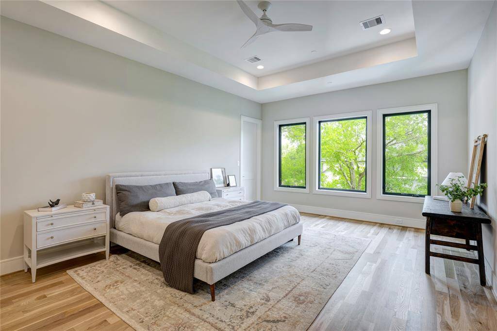 Retreat to the primary suite with its tray ceiling and three large windows that capture the northern sun. The primary suite features two walk-in closets, with one connected to a secondary bedroom—offering flexibility as a private office, gym, nursery, or expanded primary closet for those who don't need the sixth bedroom.