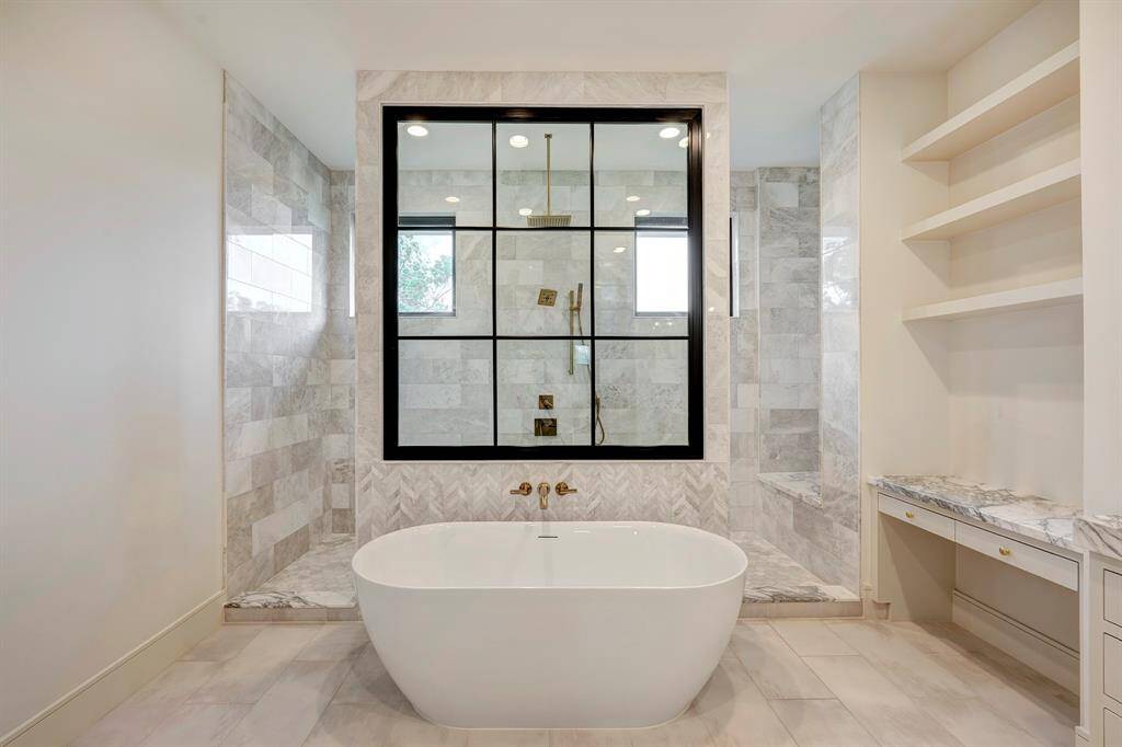 Luxurious spa-inspired primary bathroom showcases a freestanding soaking tub, dual vanities with quartzite countertops, a built-in makeup station, and%