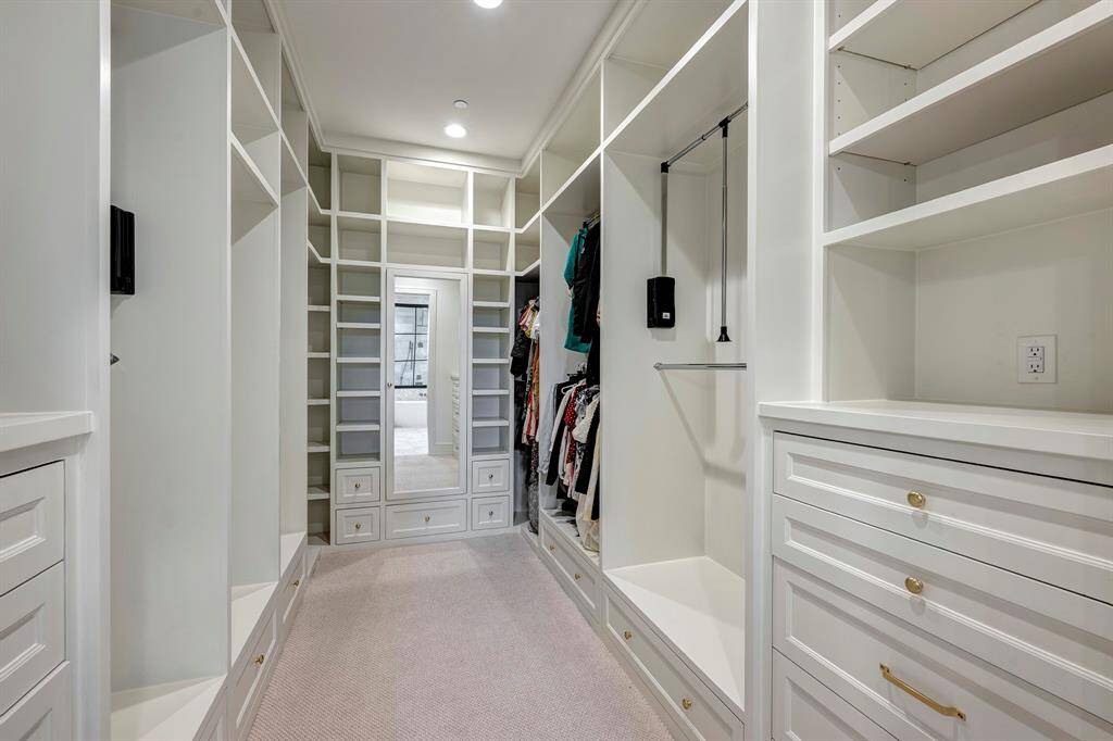 One of two spacious walk-in closets featuring custom built-ins, shelving, and storage solutions for all clothing and accessories.