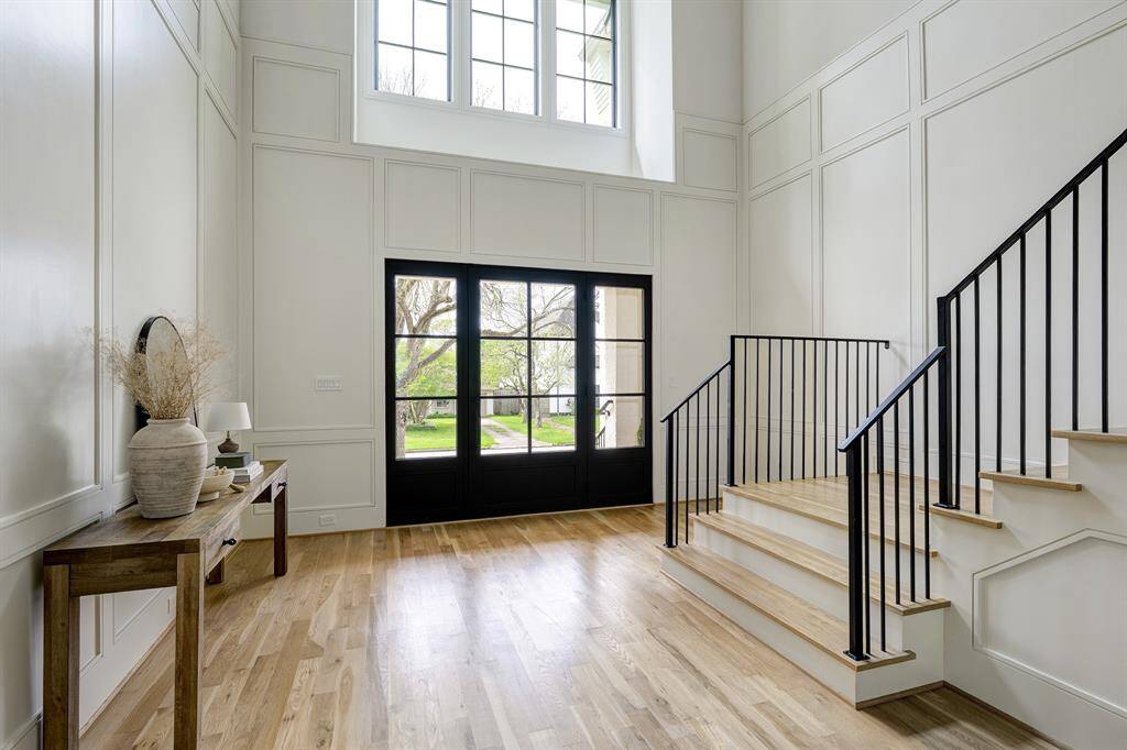 View of the grand two-story foyer leading to the front entrance, highlighting the custom metal-and-glass door (9 ft wide × 8 ft tall with a 4-ft opening).