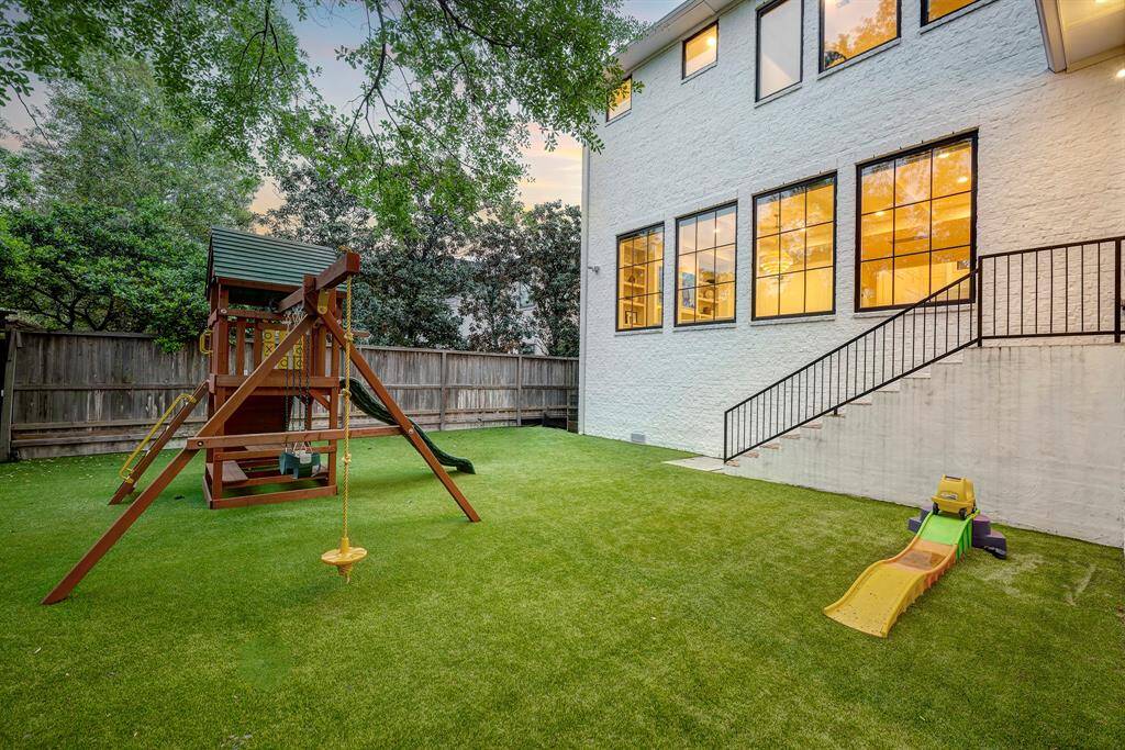The low-maintenance backyard showcases pristine artificial turf surrounded by elegant landscaping, featuring a putting green area with ample space for a future pool.
