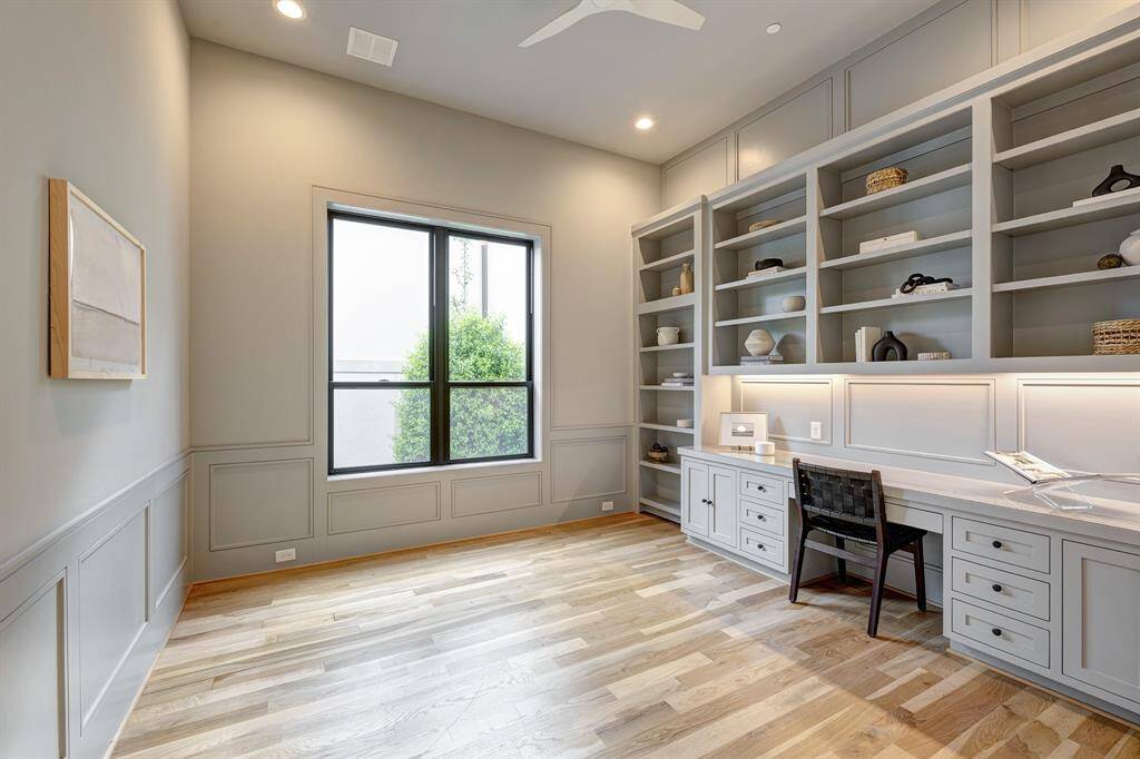 Conveniently located between the foyer and living room is the dedicated office/playroom with glass French doors, custom inset cabinetry, wainscot paneling, and a secret hidden closet concealed behind the bookshelf and secured with magnets.