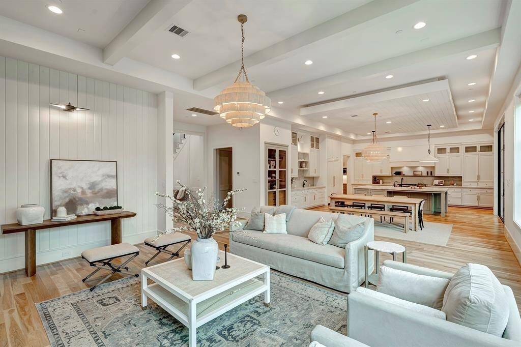 Seamlessly blending sophistication with functionality, this open-concept kitchen, dining and living space is the heart of the home. Overhead, a reversed tray ceiling with T&W wood panel detailing adds architectural interest, complemented by designer pendant lighting. The adjoining living area offers plush seating, a soft neutral palette, and oversized windows that flood the space with natural light and offer serene backyard views. Ideal for effortless entertaining or cozy evenings at home.