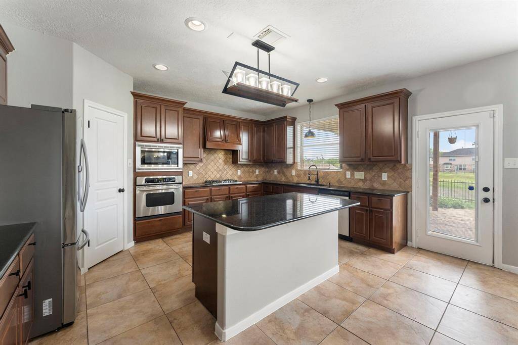 Island kitchen with updated light fixtures, stainless steel appliances and huge corner pantry.