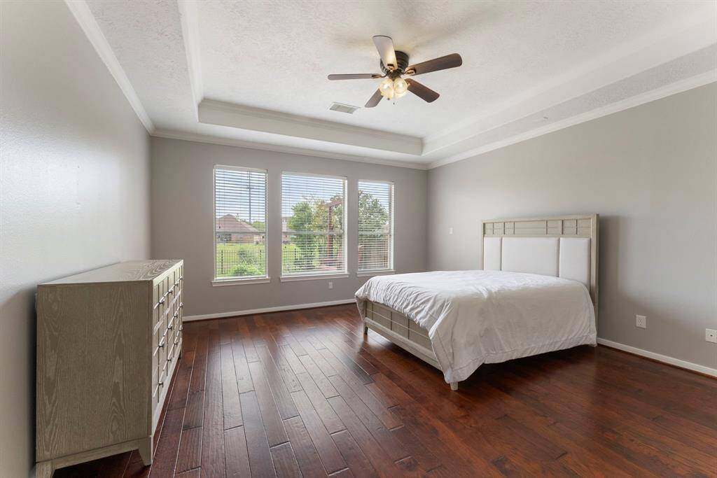 Primary suite privately tucked away on the first floor with high trey ceiling, and a wall of windows overlooking the backyard, pool and lake.