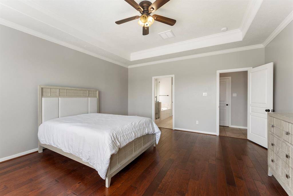 Crown moulding, hardwood floors, ceiling fan and neutral paint in this private primary downstairs.
