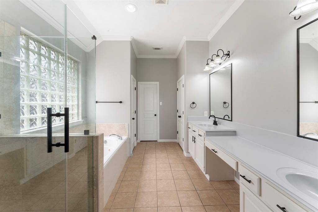 Primary bathroom with updated frameless glass shower, double sink vanity and large walk-in closet.