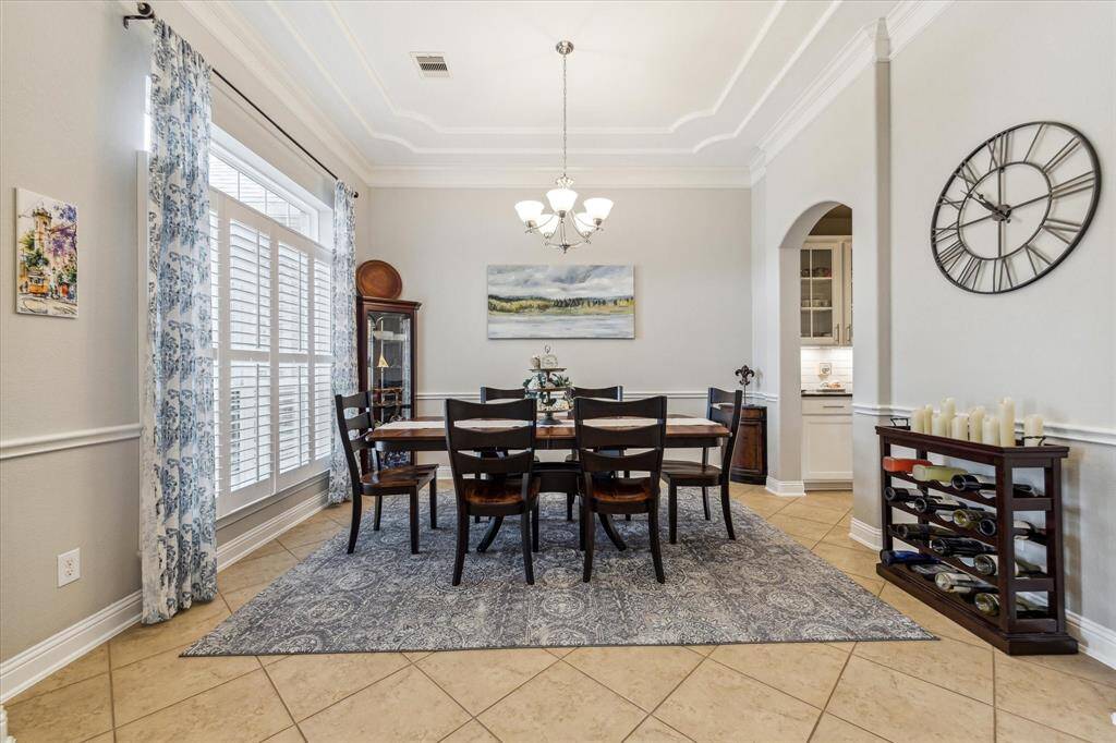 This large dining room is perfect for entertaining! Plantation shutters, coffered ceilings with crown molding complete the space. Butler's pantry connects the kitchen