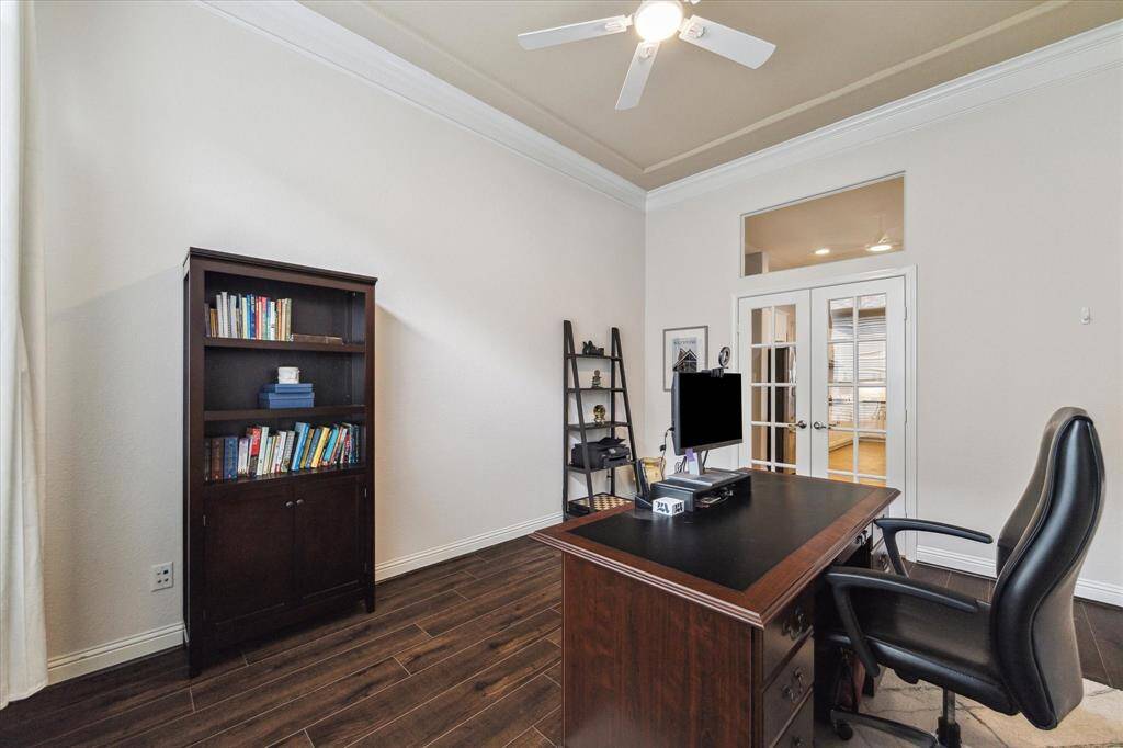 View of the home office with wood floors, French doors, window transom, ceiling fan.