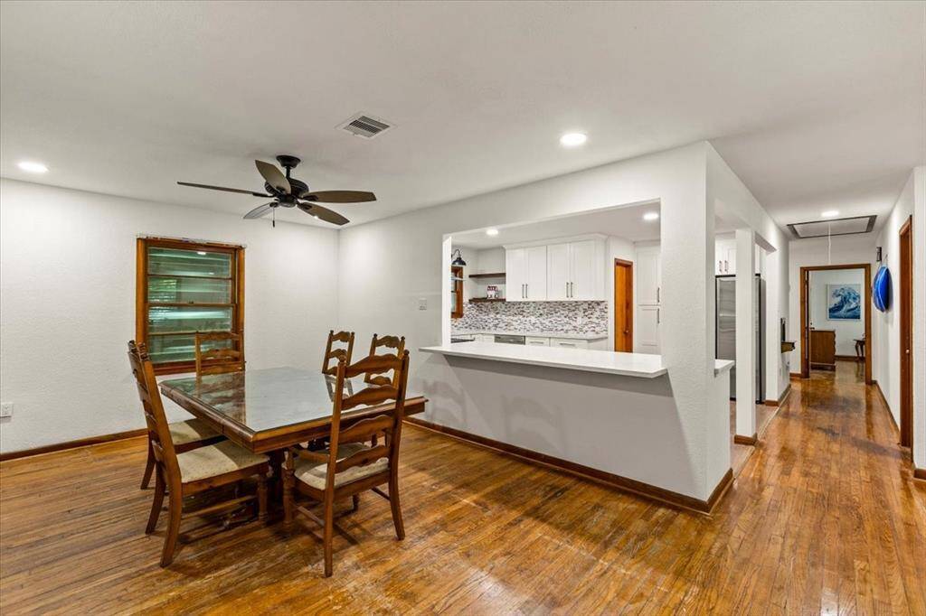 Dining room is adjacent to a recent renovated kitchen featuring white cabinets and a mosaic backsplash. The room has hardwood floors, recessed lighting, and a ceiling fan for comfort. The open layout enhances the space, creating a seamless flow between dining and cooking areas, ideal for entertaining.