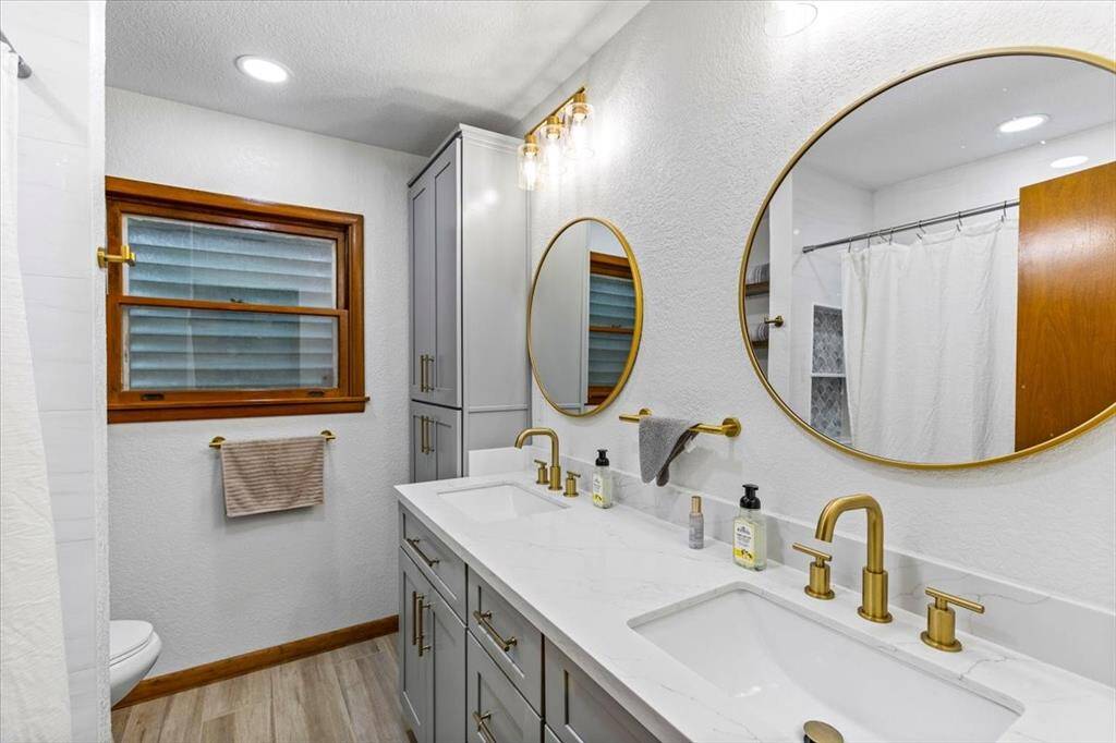 Recently updated bathroom features a modern double vanity with gold fixtures.