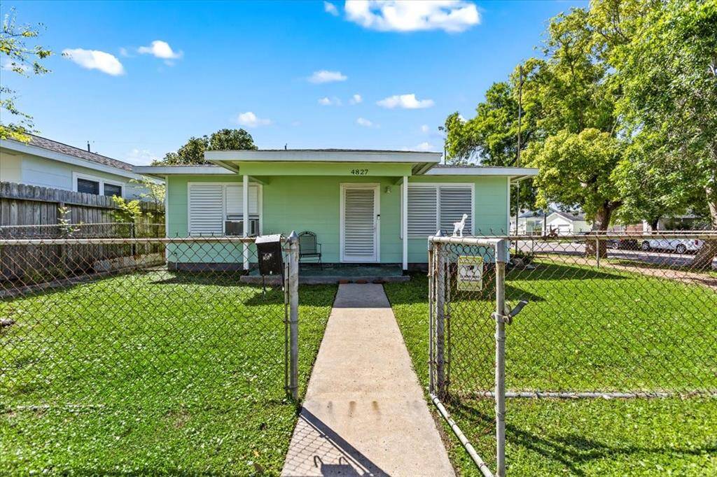 Single-story home with a pastel exterior, featuring a covered front porch and a fenced yard.