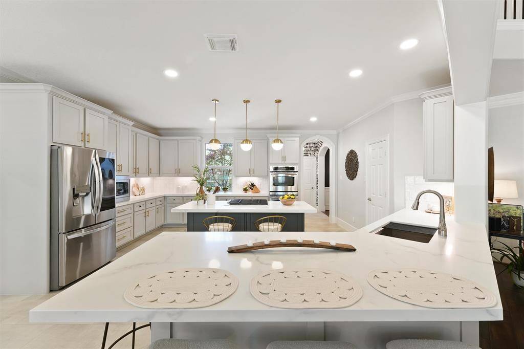 This luxuriously remodeled kitchen (2024) has everything you need to cook gourmet meals and entertain. The expansive quartz countertops and under-lit shaker cabinets line the perimeter of the kitchen. In addition to the breakfast bar, the gas range island highlights the heart of the home with gold pendant lighting and more seating. The high-end stainless steel appliances complete this impressive space.