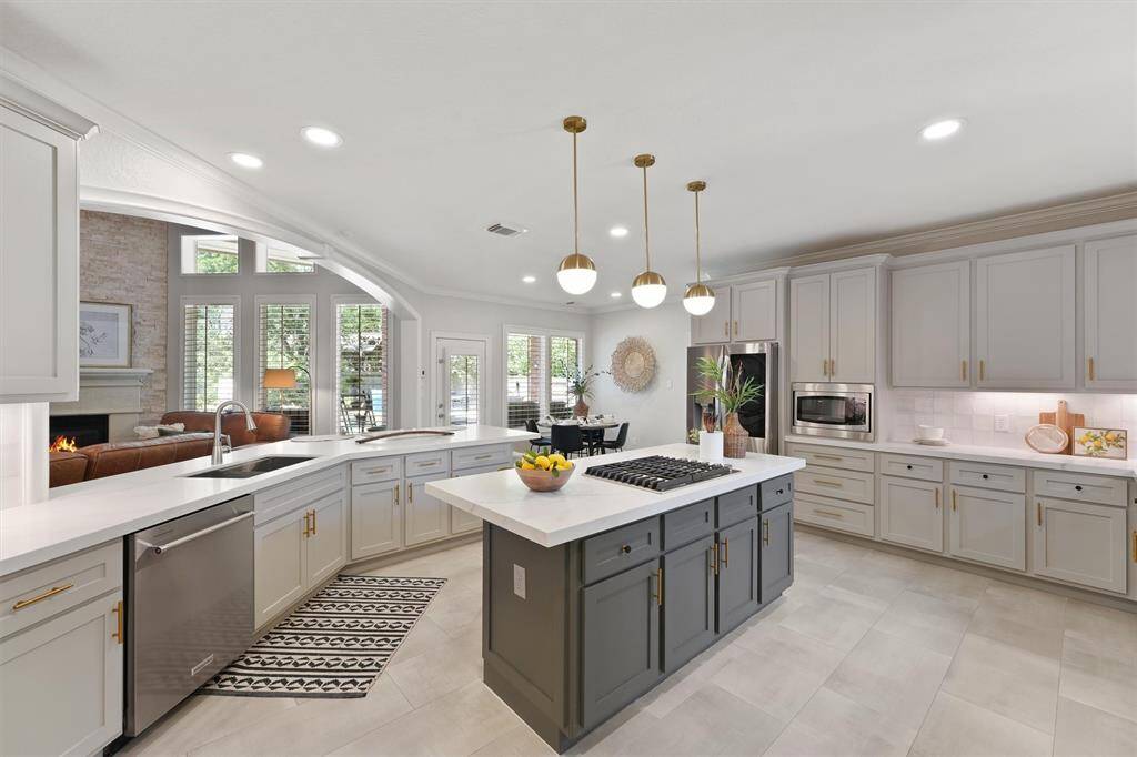 This stunning island kitchen is the heart of the home with top of the line, stainless steel appliances, a gas island range, quartz countertops and shaker cabinets accented with gold hardware. Recessed, pendant, and undercabinet lighting throughout the space. Elegant tile flooring.