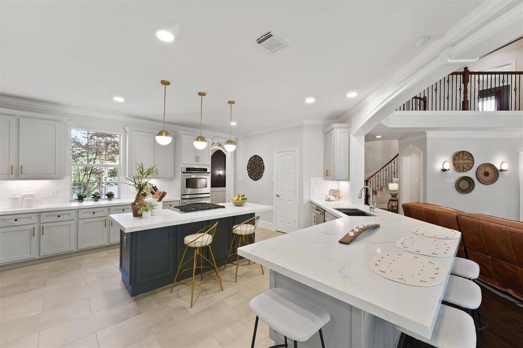 This open kitchen has an impressive breakfast bar, more seating at the gas island, large window with a beautiful view, and walk-in pantry.