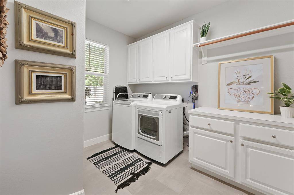 The laundry room has a large storage cabinets, a quartz countertop folding station, and a window for natural light in the space.