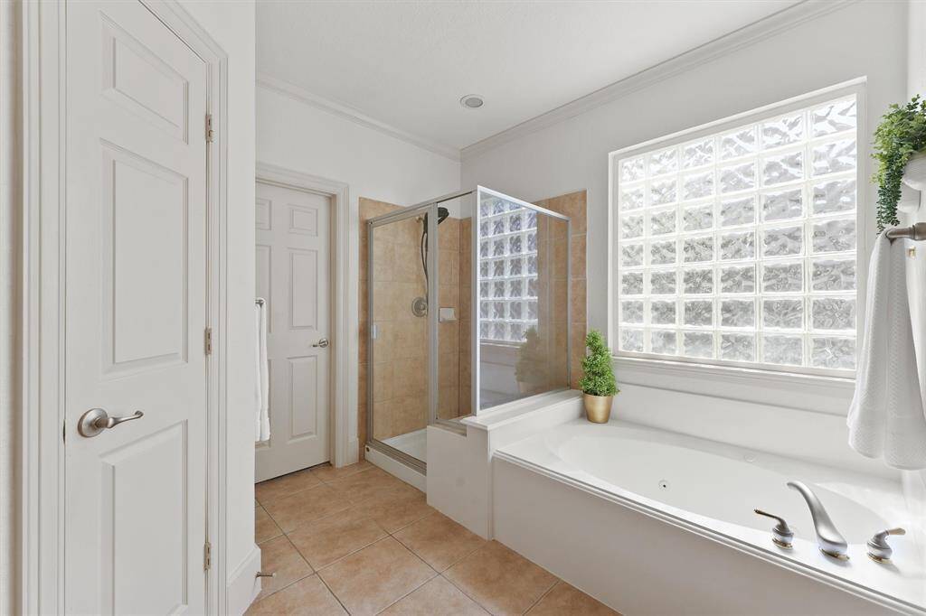 There is a frosted block window above the jetted tub and large framed shower. The space also features an impressive walk-in closet.