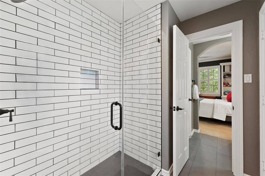 Updated shower featuring subway tile and framless glass shower adjoins the vanity areas in this spacious and functional jack and jill bathroom.