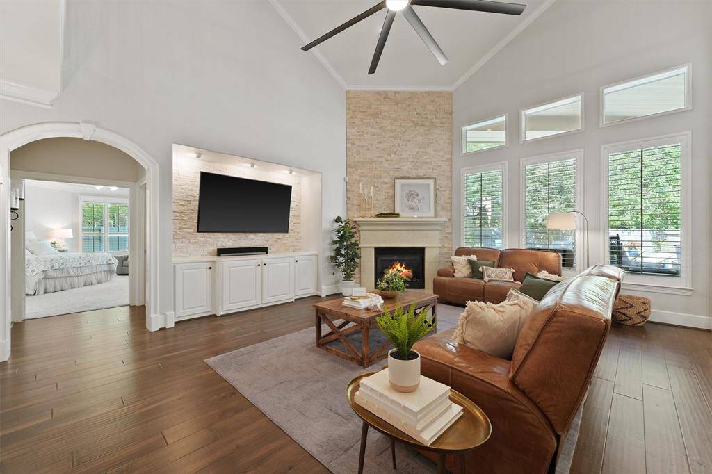 The living room also features a custom stone accented backlit TV space with built-in cabinetry, and views of the backyard oasis from the large windows.