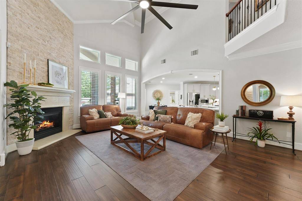 The spacious family room has soaring high ceilings, a beautiful stone accented gaslog fireplace, and large windows for natural lighting.