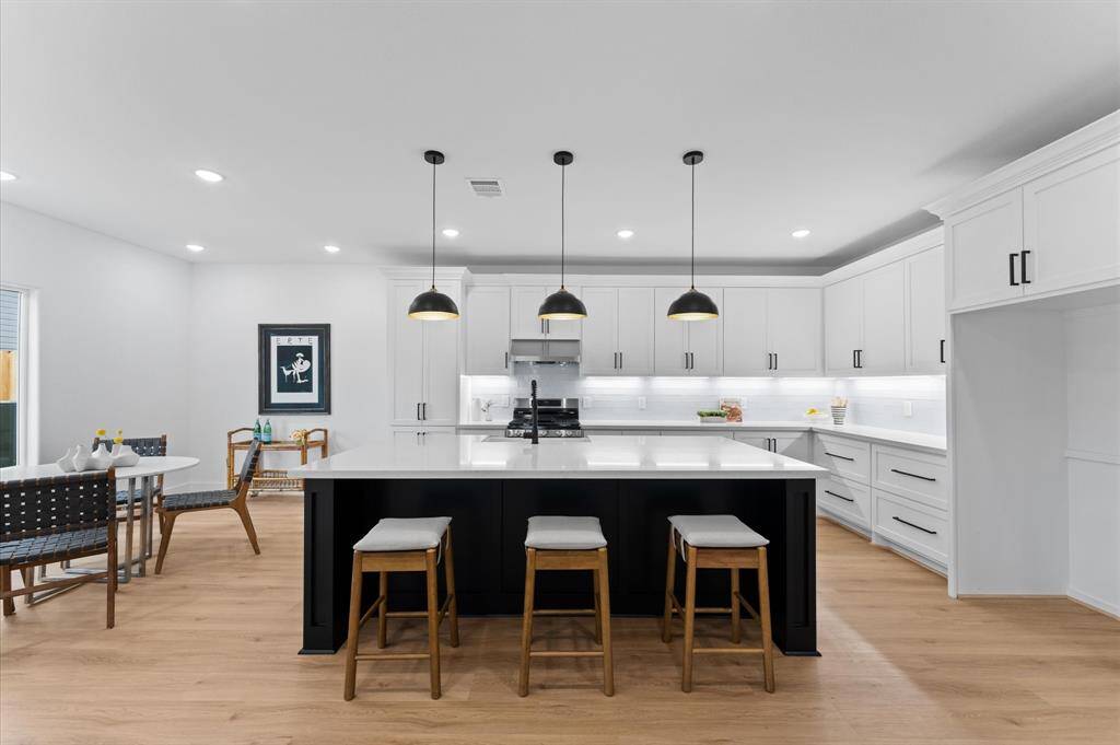 A picture-perfect island kitchen features a breakfast bar under mounted lights.