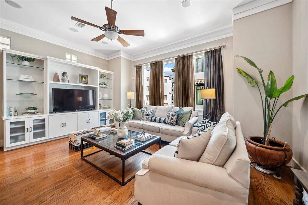 The living area features an expansive built-in with glass shelving, cabinet storage, and space for a wide-screen TV—offering both function and a sleek focal point.