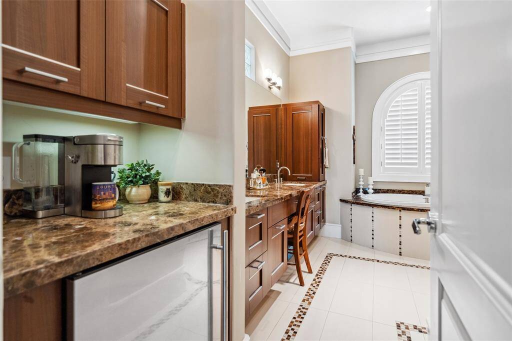 A well-appointed coffee bar with cabinetry and a built-in beverage fridge connects the primary bedroom to the en suite bath—adding convenience to your morning routine.