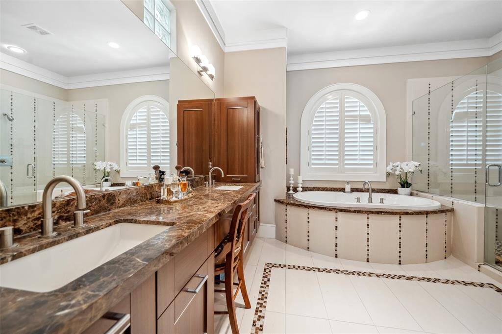 The primary bath features rich dark wood cabinetry with double sinks and a built-in makeup vanity. From this view, you can also see the soaking tub and walk-in shower tucked beyond.