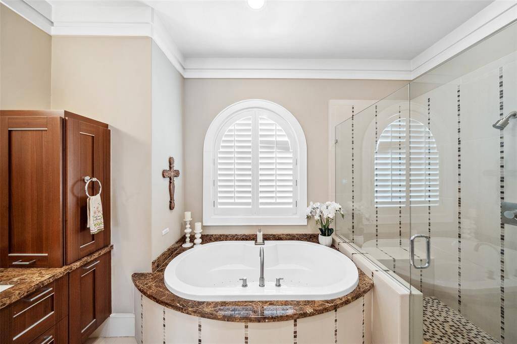 A closer look reveals the frameless walk-in shower and a sculptural, jetted soaking tub with an elegant granite and tile surround