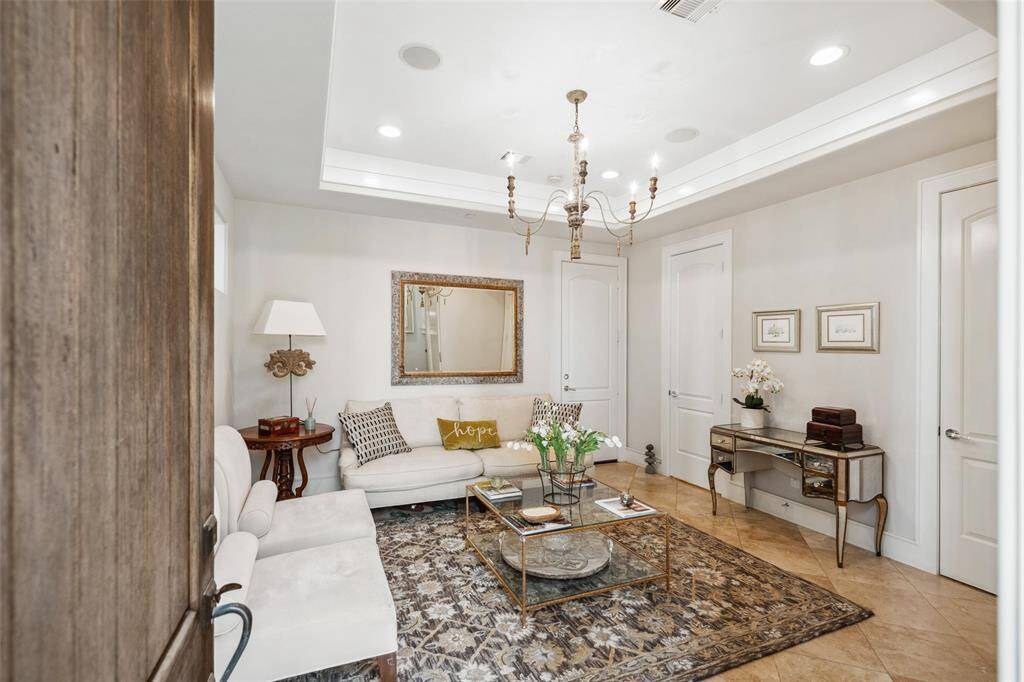 Just off the front entry, a first-floor reception room offers a warm welcome with a tray ceiling, recessed lighting, and an elegant chandelier—perfect as a sitting area or stylish greeting space.