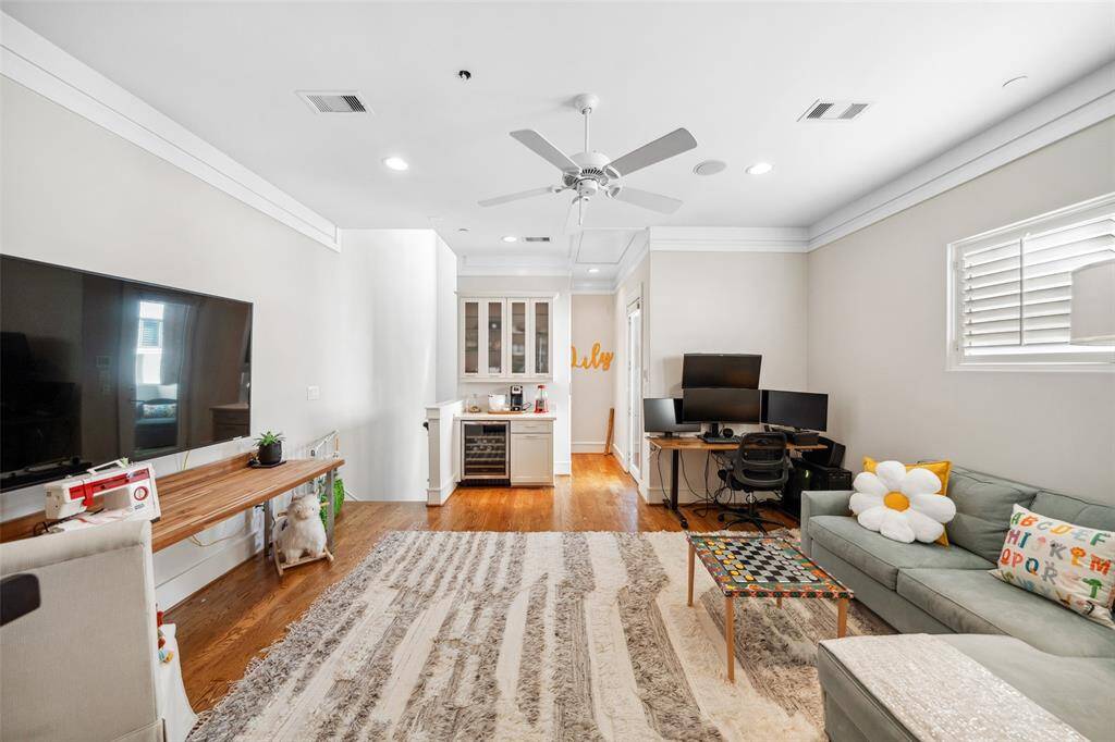 Another angle of the flex space reveals a built-in dry bar with a beverage fridge and glass-front upper cabinets—perfect for entertaining or winding down. A glass door leads out to the fourth-floor balcony, extending the living space outdoors.