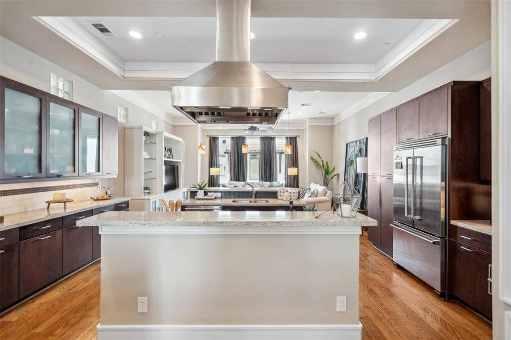 The kitchen is anchored by a double island—perfect for casual seating and staying connected to the action while cooking or entertaining. An abundance of custom cabinetry, including elegant glass-front uppers, adds both style and storage.