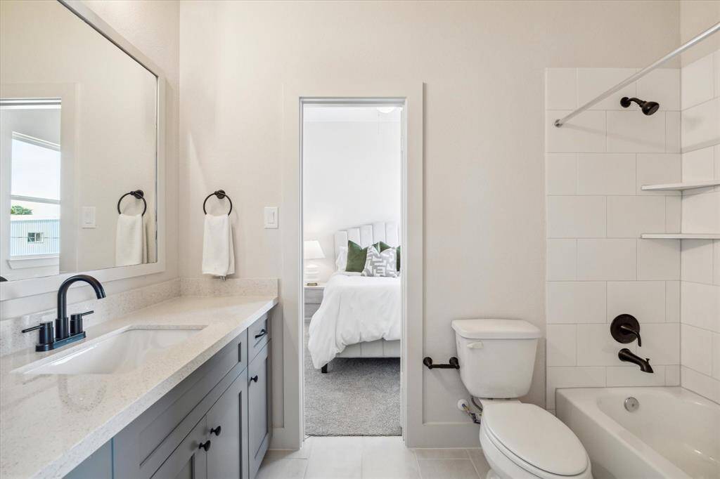 This stylish Hollywood bathroom features a sleek vanity with quartz countertops, matte black fixtures, and a shower/tub combo—offering direct access from one of the secondary bedrooms for added convenience.
