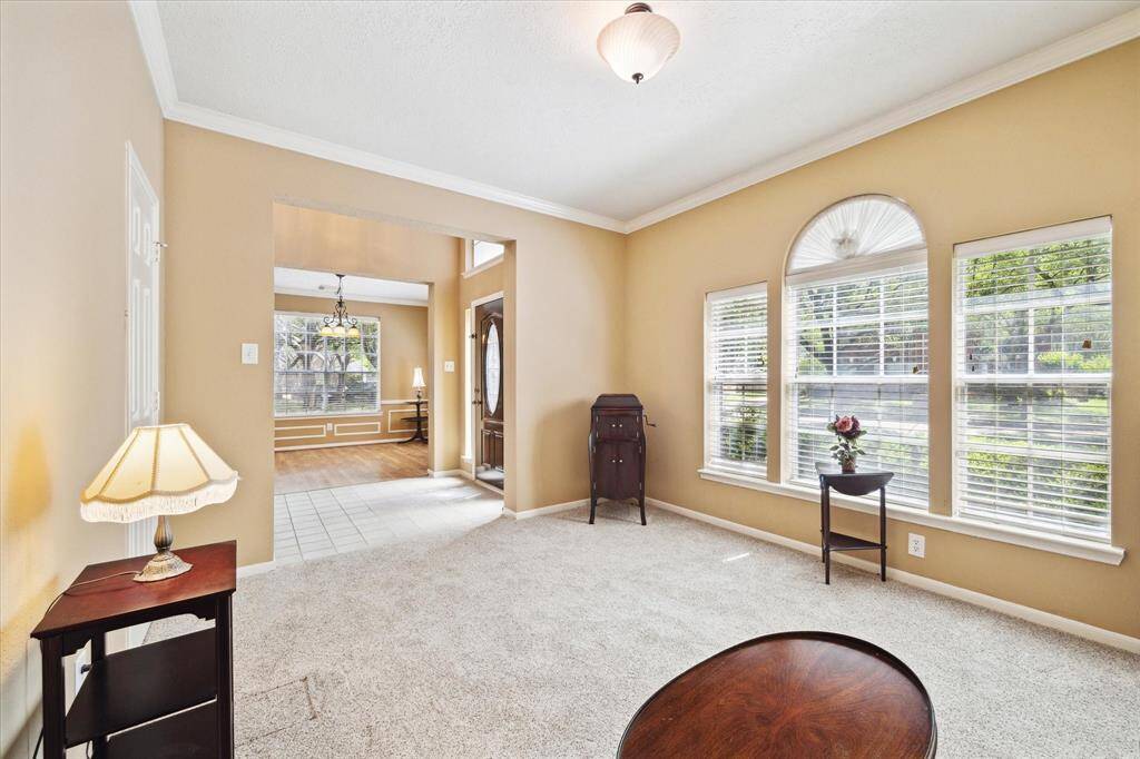 Elegant formal living room with soft neutral tones, plush carpeting, and expansive windows offering picturesque views of Rebel Ridge Dr.