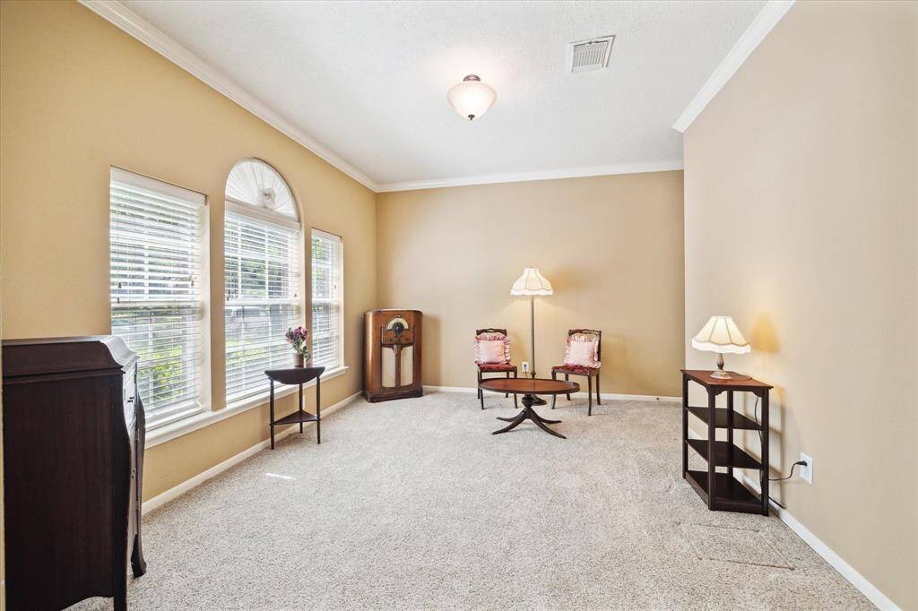 Relax in this spacious living room featuring neutral tones and plush carpet, ideal for unwinding with a good book.