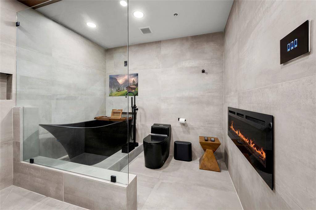 Primary bathroom featuring a color changing fireplace and a bath tub with a smart television