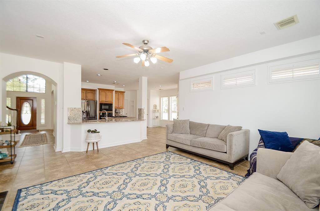 View of the den from the back of the house.  Foyer is seen on the left.  Kitchen is open to the den via an extended breakfast bar with room for several stools to provide additional dinner guests.  Don't you just love the shuttered windows above the sofa for light with privacy?