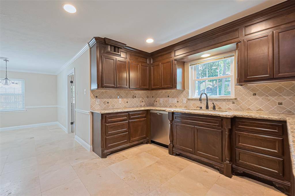 Elegant kitchen with sleek granite countertops and a stylish tile backsplash with Travertine flooring.