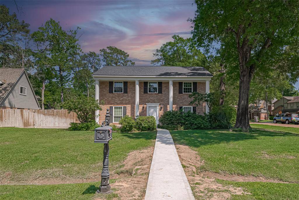 Charming two-story brick home with classic columns, surrounded by mature trees. Features a spacious front yard, and a welcoming pathway. Ideal for buyers seeking a blend of traditional elegance and modern comfort.